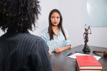 Two people talking at a desk.