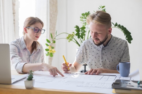 a man signing a paper a woman is pointing at
