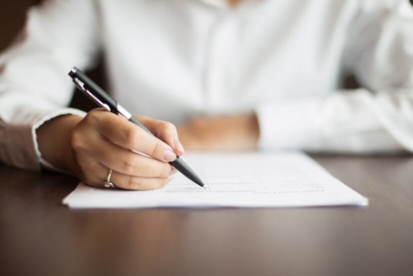 a woman signing a paper.