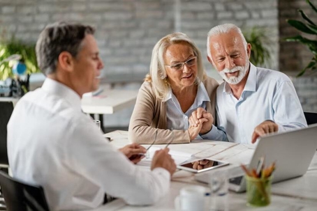 a elderly couple looking at a laptop with a man.