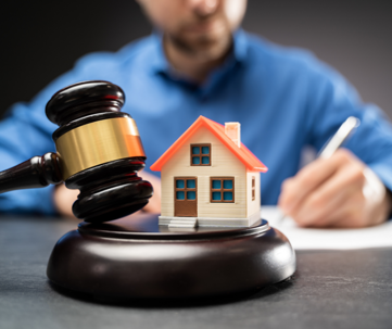 a man with a gavel and toy house.
